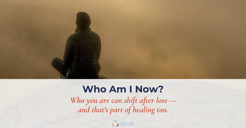 Person sitting on a foggy mountaintop at sunrise, representing the search for identity through grief and loss