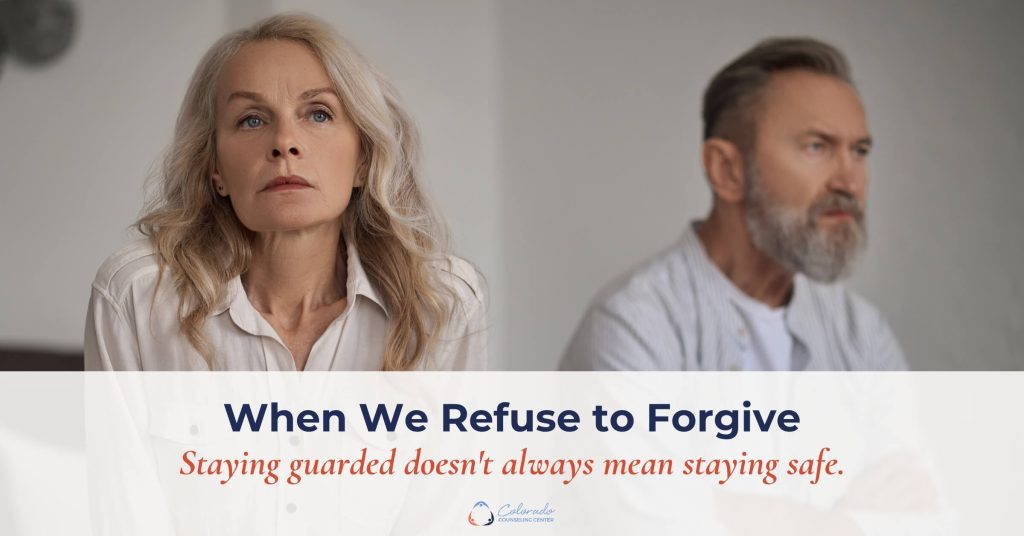 Older couple sitting apart with arms crossed, conveying emotional distance and refusal to forgive
