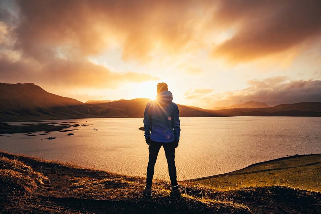 Person standing at the edge of a lake at sunrise, looking toward the horizon &mdash; what to expect from individual counseling.