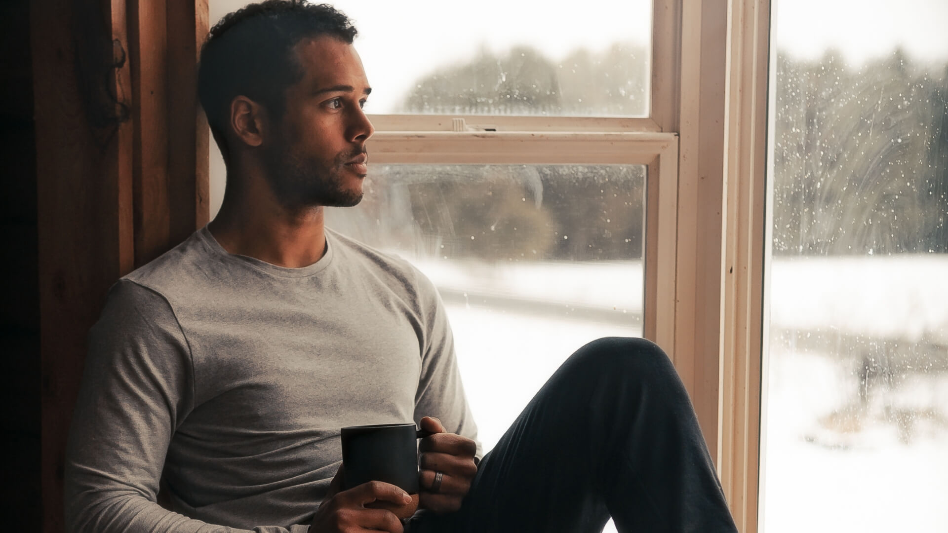 Man sitting quietly by a window, reflecting during individual counseling for relationship issues in Greenwood Village Centennial