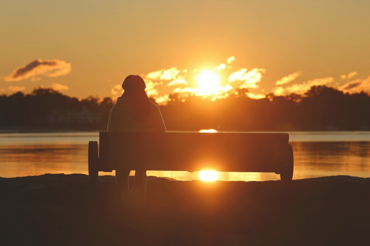 Person sitting alone at sunset, representing healing through grief counseling and therapy